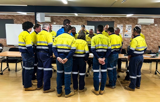 Mining worker huddled around Talisman team member